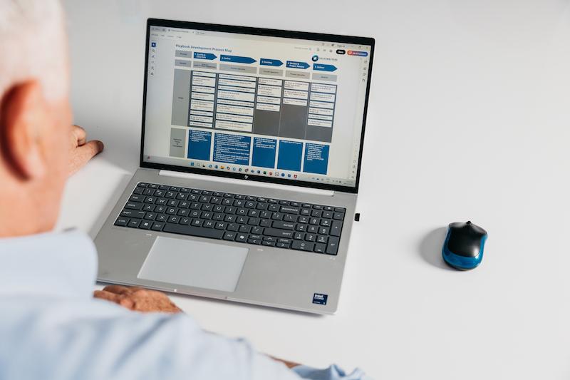 A man at a laptop looking at a sales process plan.